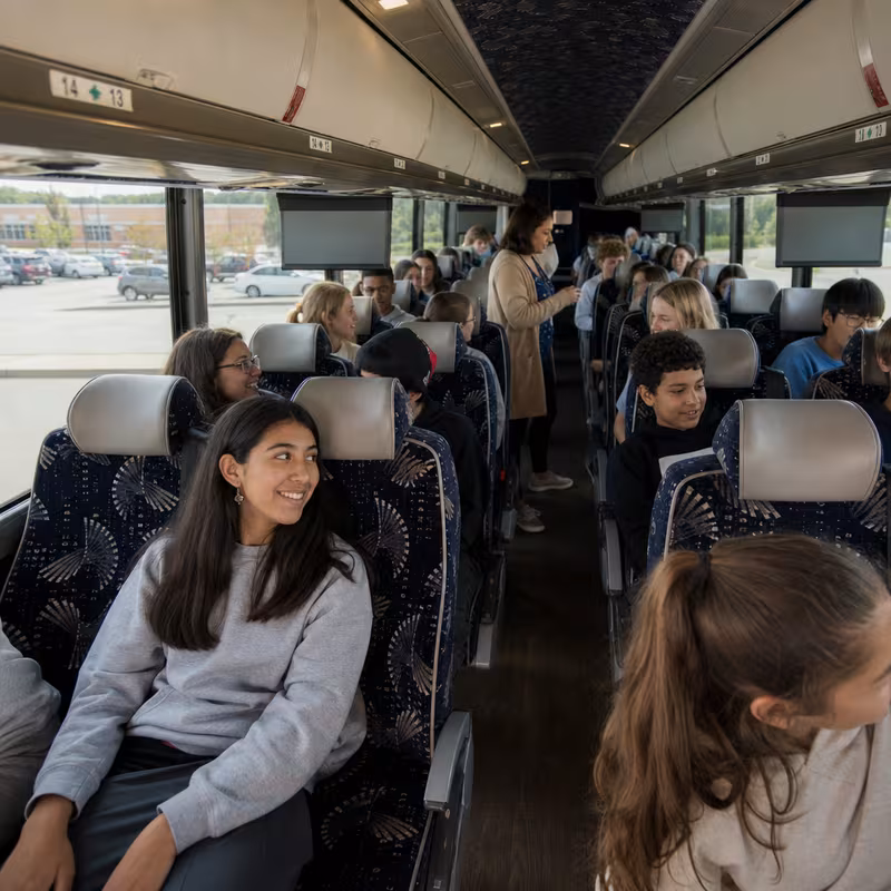Group boarding a white charter bus for School Transportation transportation in Des Moines